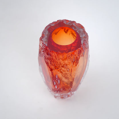 Amber orange art glass decorative vase with clear glass outer body and elongated oval form.