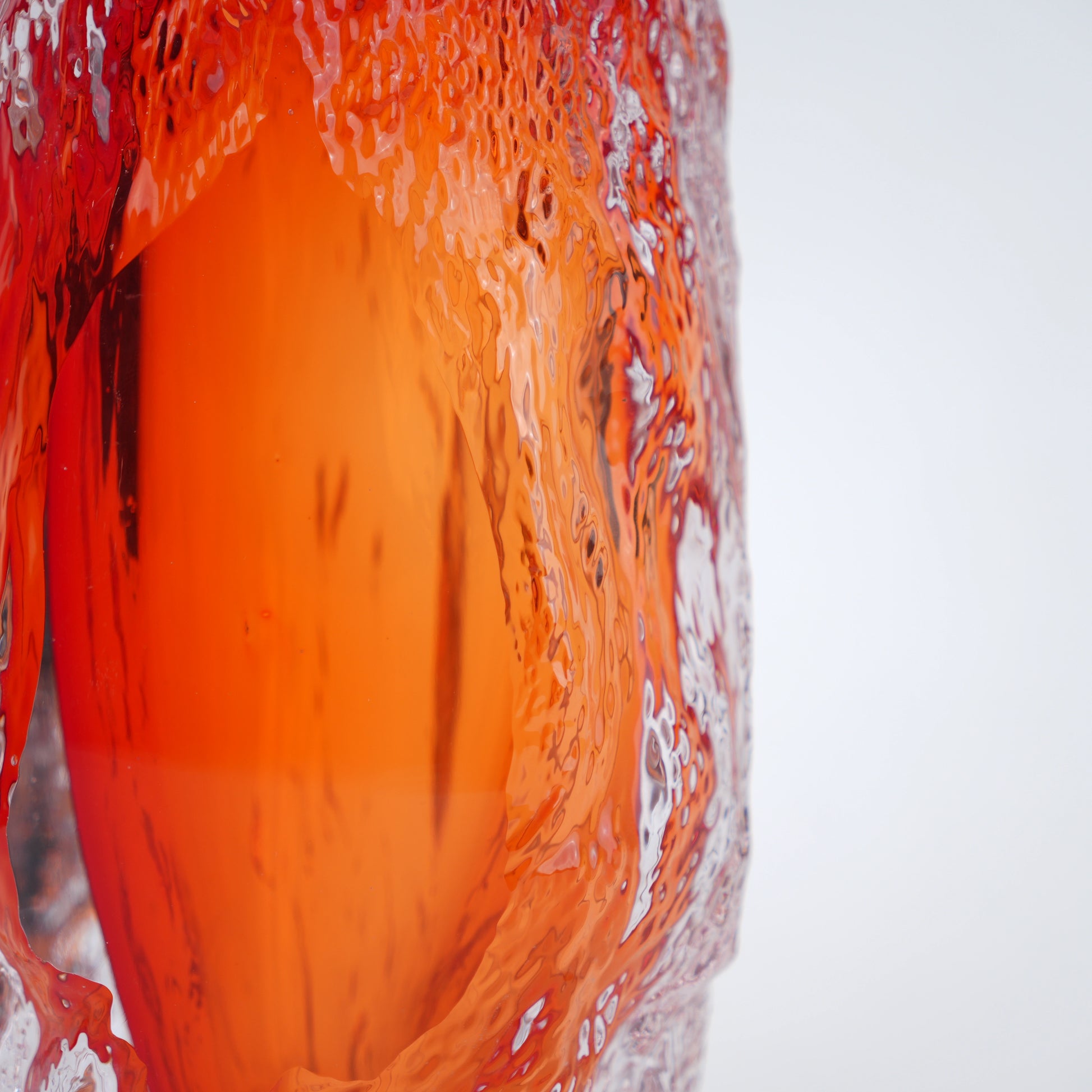 Amber orange art glass decorative vase with clear glass outer body and elongated oval form.