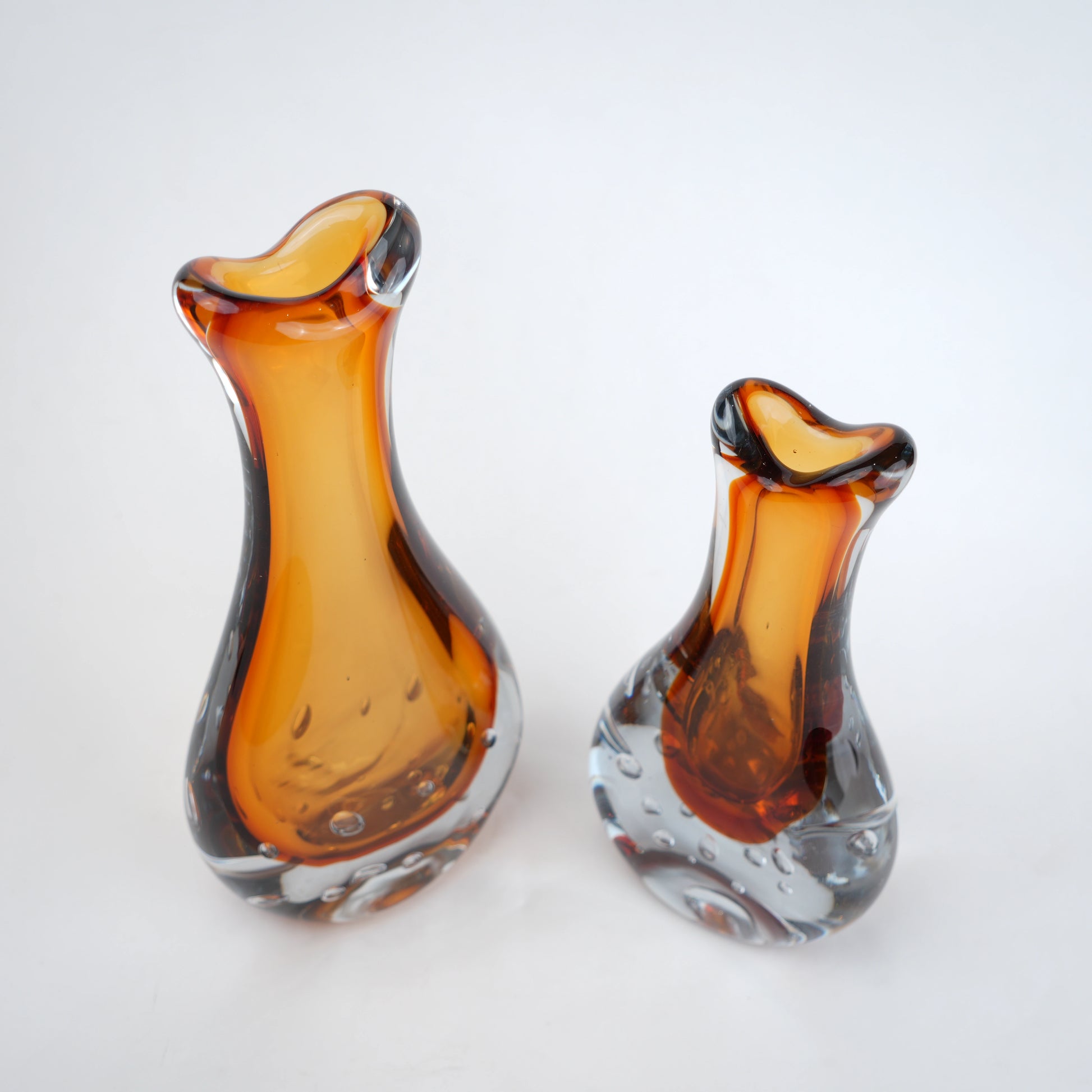 Amber clear art glass decorative vase with layered color center and elongated glass form.