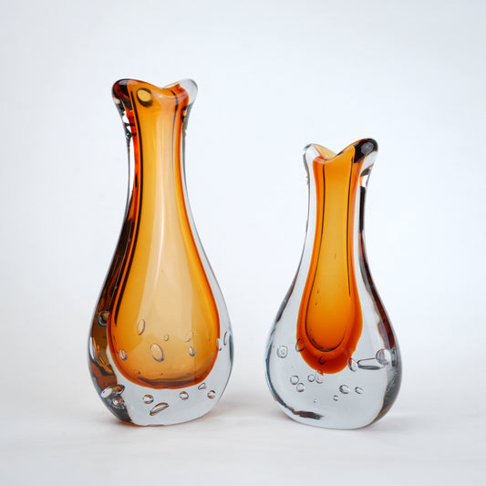 Amber clear art glass decorative vase with layered color center and elongated glass form.