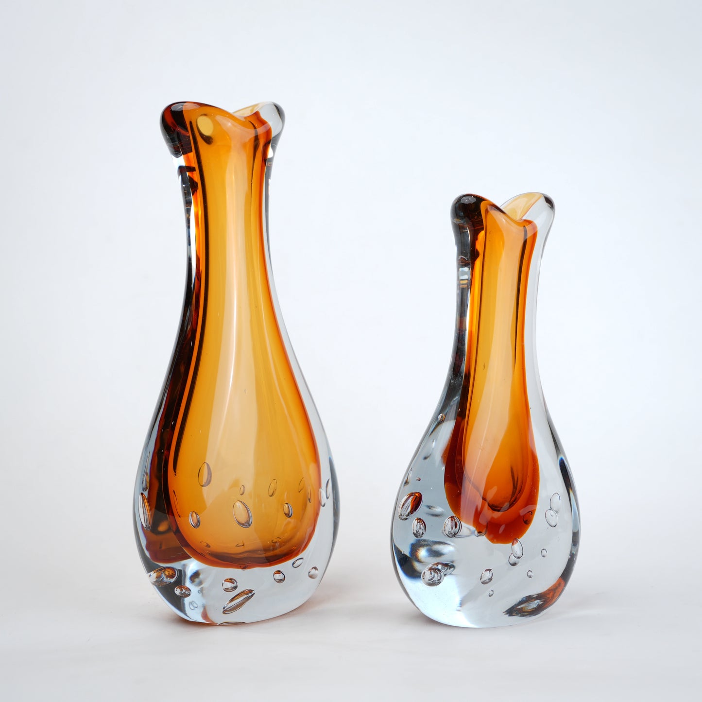 Amber clear art glass decorative vase with layered color center and elongated glass form.