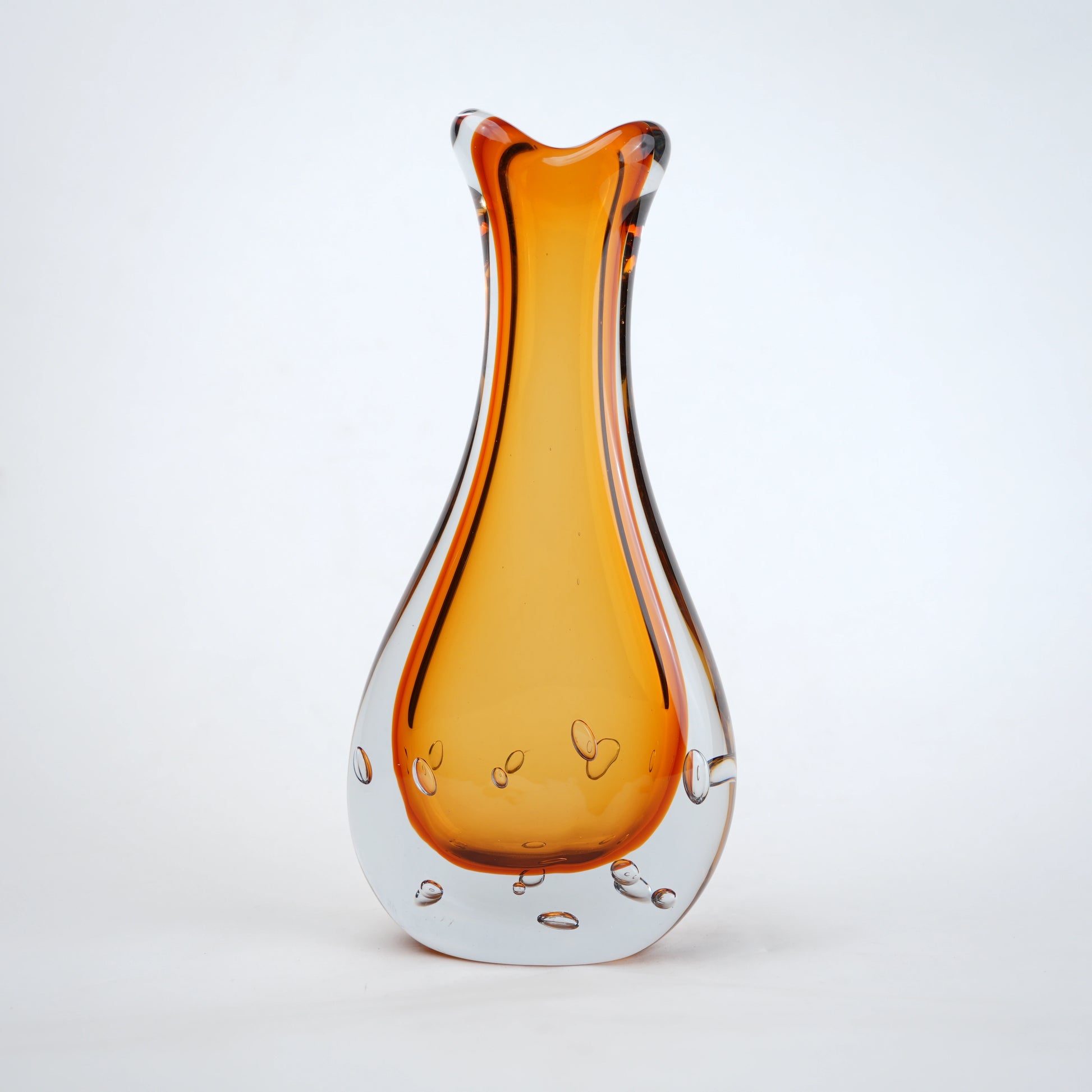 Amber clear art glass decorative vase with layered color center and elongated glass form.