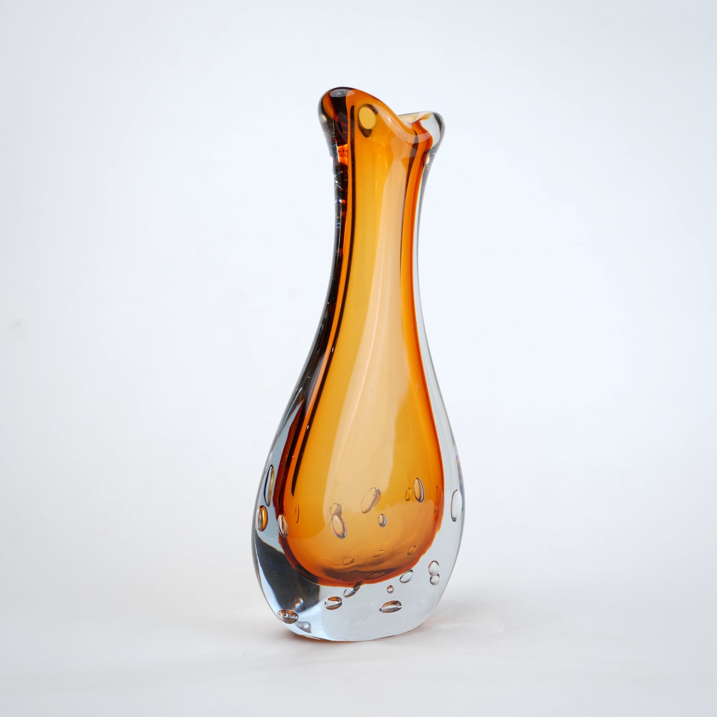 Amber clear art glass decorative vase with layered color center and elongated glass form.