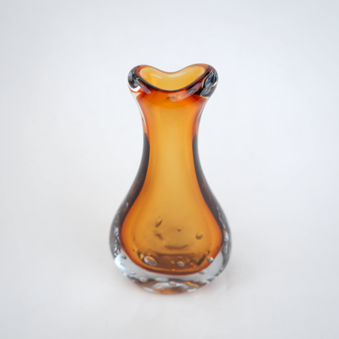Amber clear art glass decorative vase with layered color center and elongated glass form.