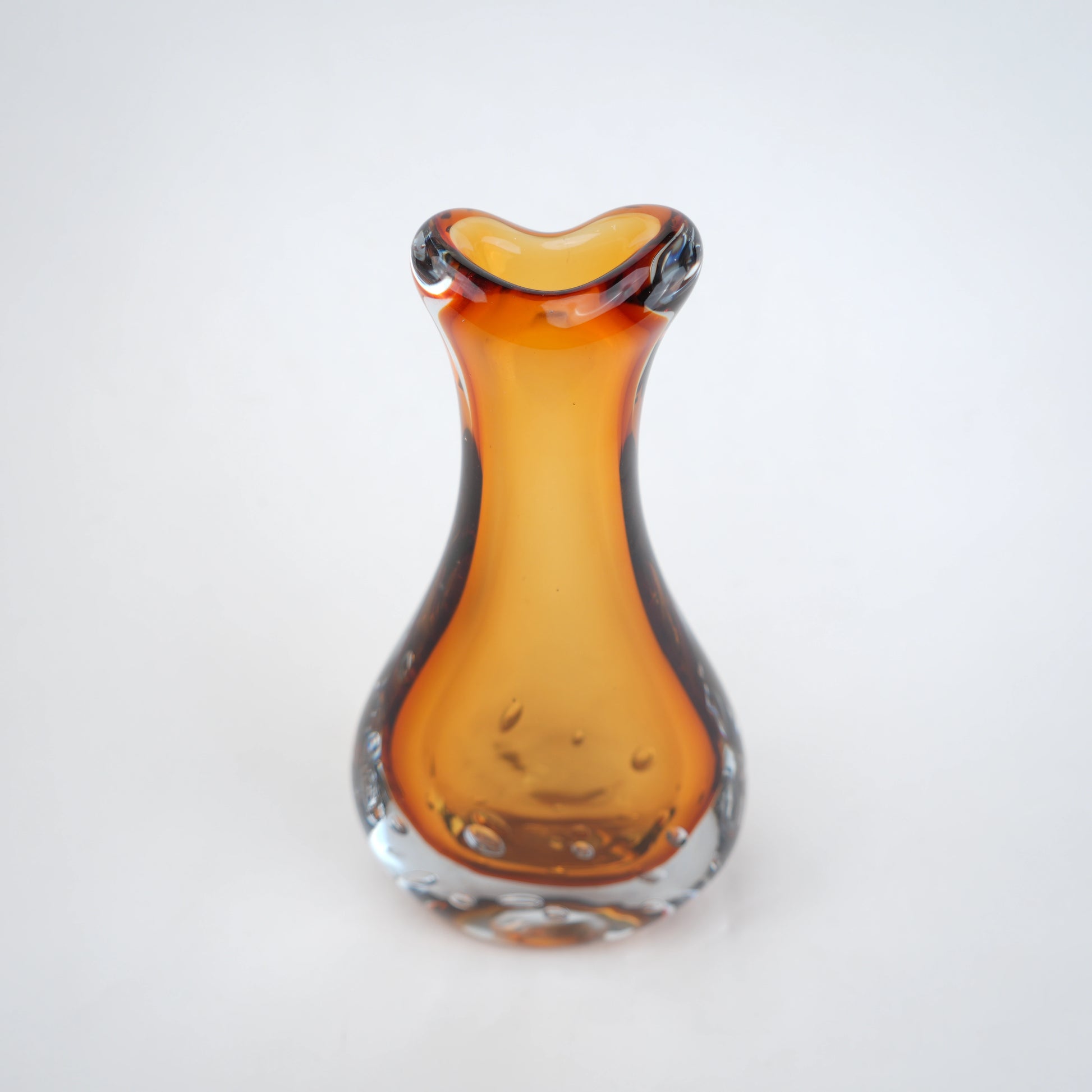 Amber clear art glass decorative vase with layered color center and elongated glass form.