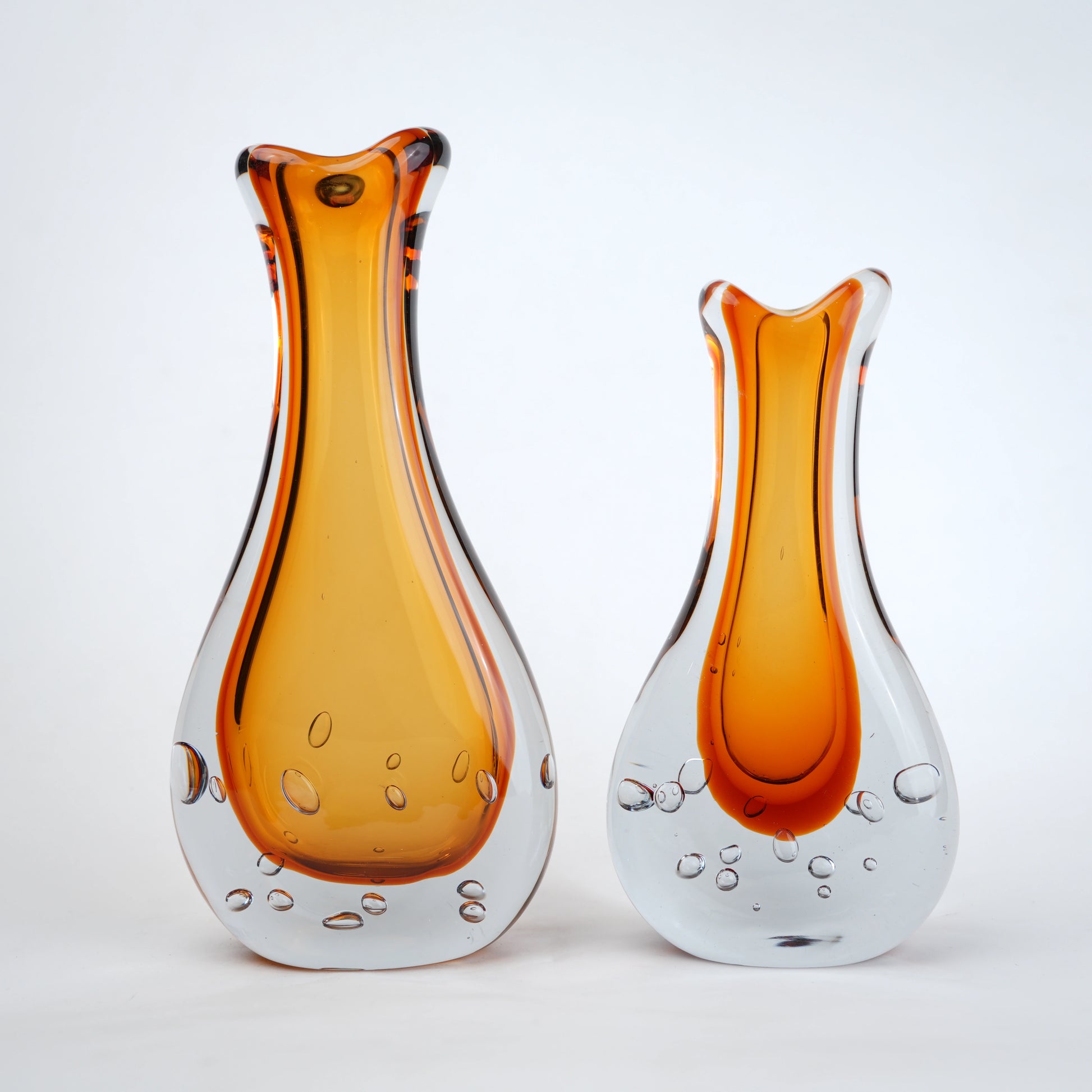 Amber clear art glass decorative vase with layered color center and elongated glass form.