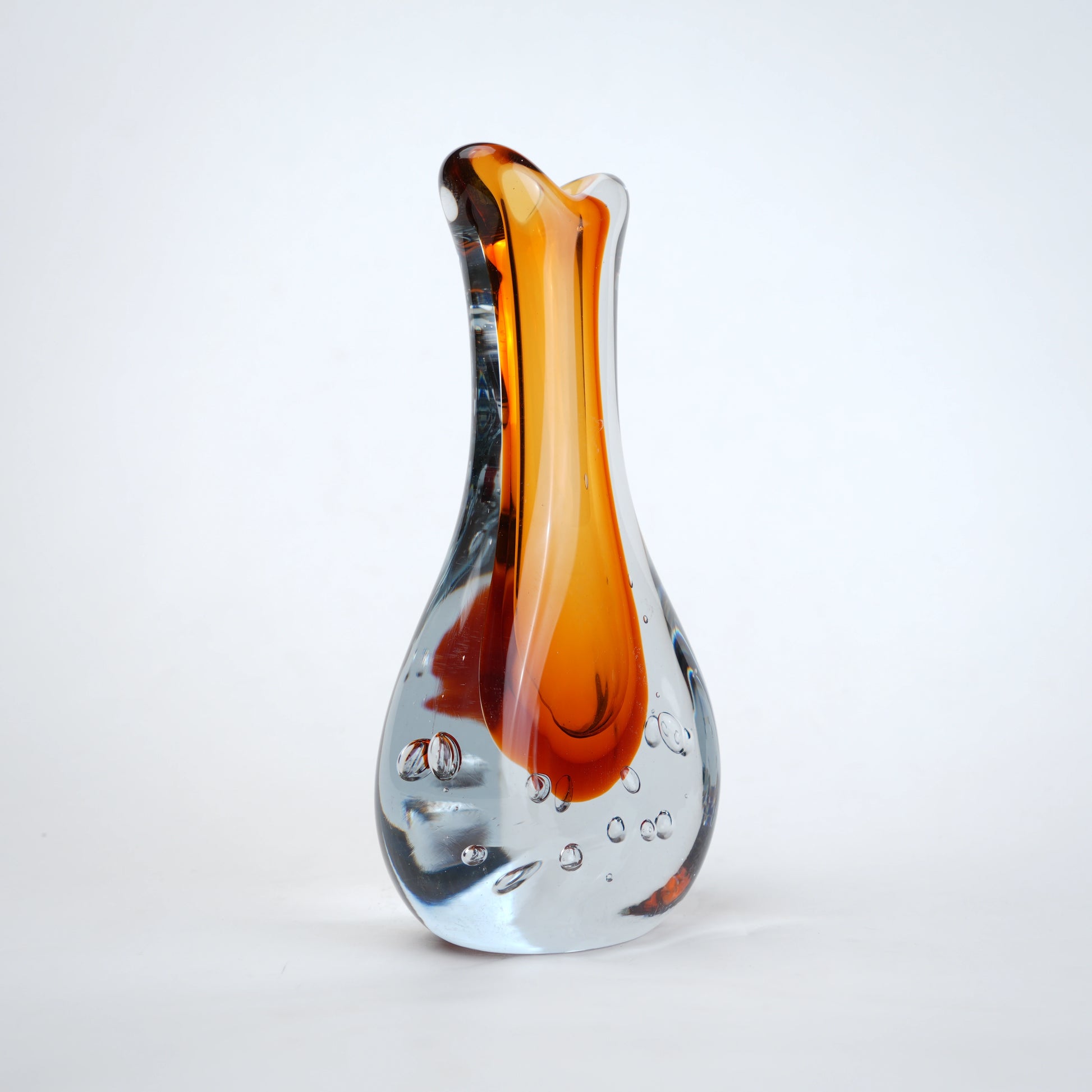 Amber clear art glass decorative vase with layered color center and elongated glass form.