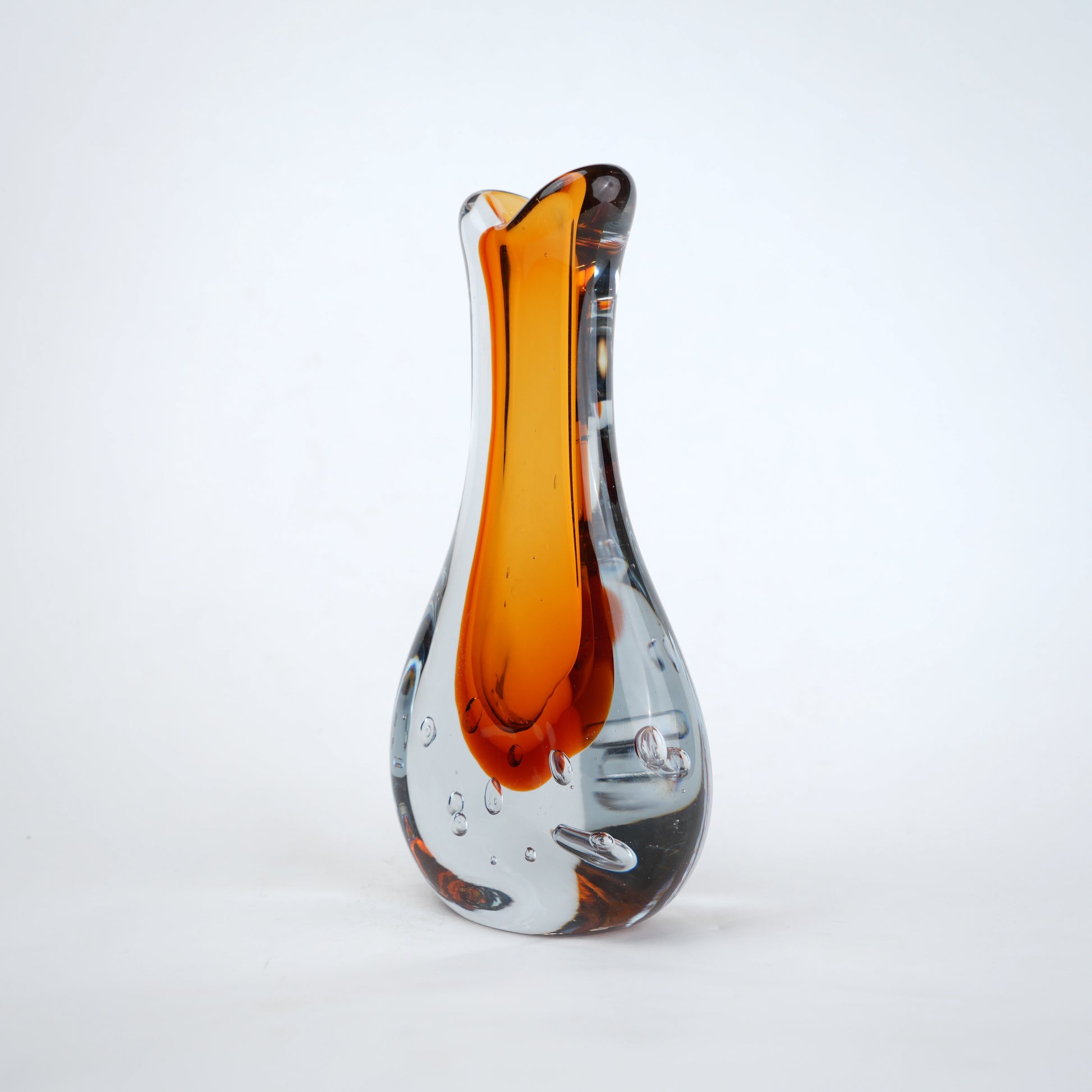 Amber clear art glass decorative vase with layered color center and elongated glass form.