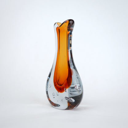 Amber clear art glass decorative vase with layered color center and elongated glass form.