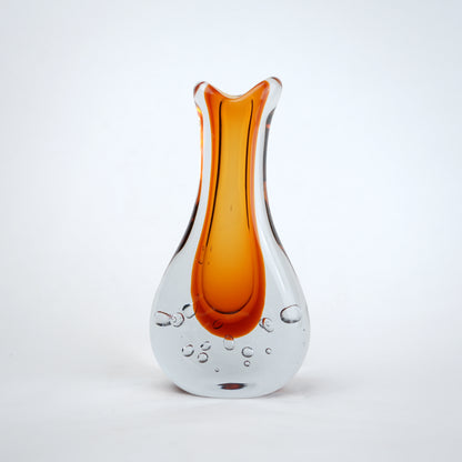 Amber clear art glass decorative vase with layered color center and elongated glass form.