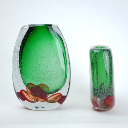 Two green glass vases with artistic designs on a white background