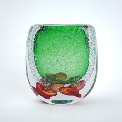 Decorative glass piece with green center and red and brown floral design on a white background
