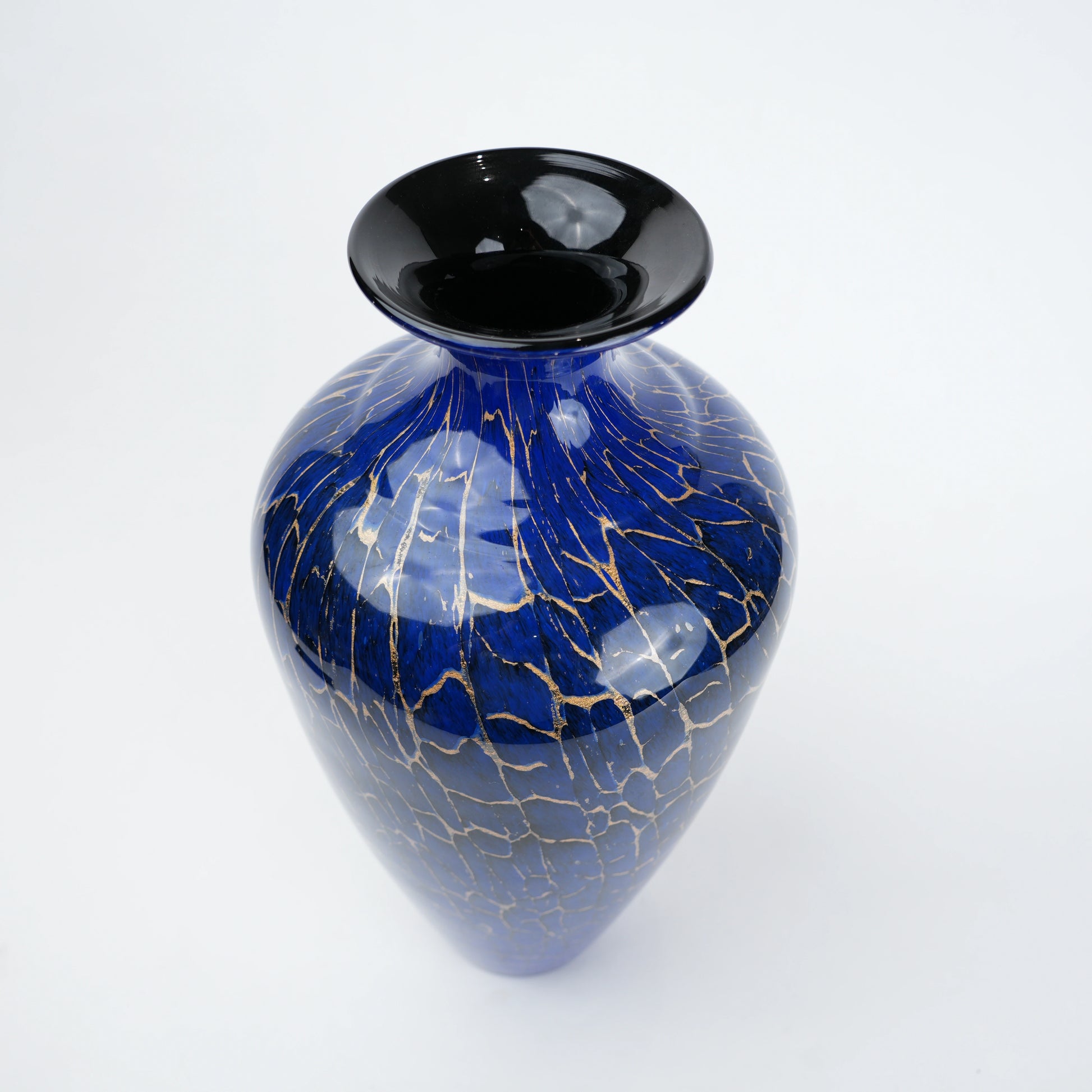 Royal blue glass vase with glossy finish featuring gold crackle detailing and rounded body with narrow neck opening