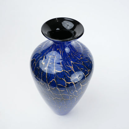 Royal blue glass vase with glossy finish featuring gold crackle detailing and rounded body with narrow neck opening