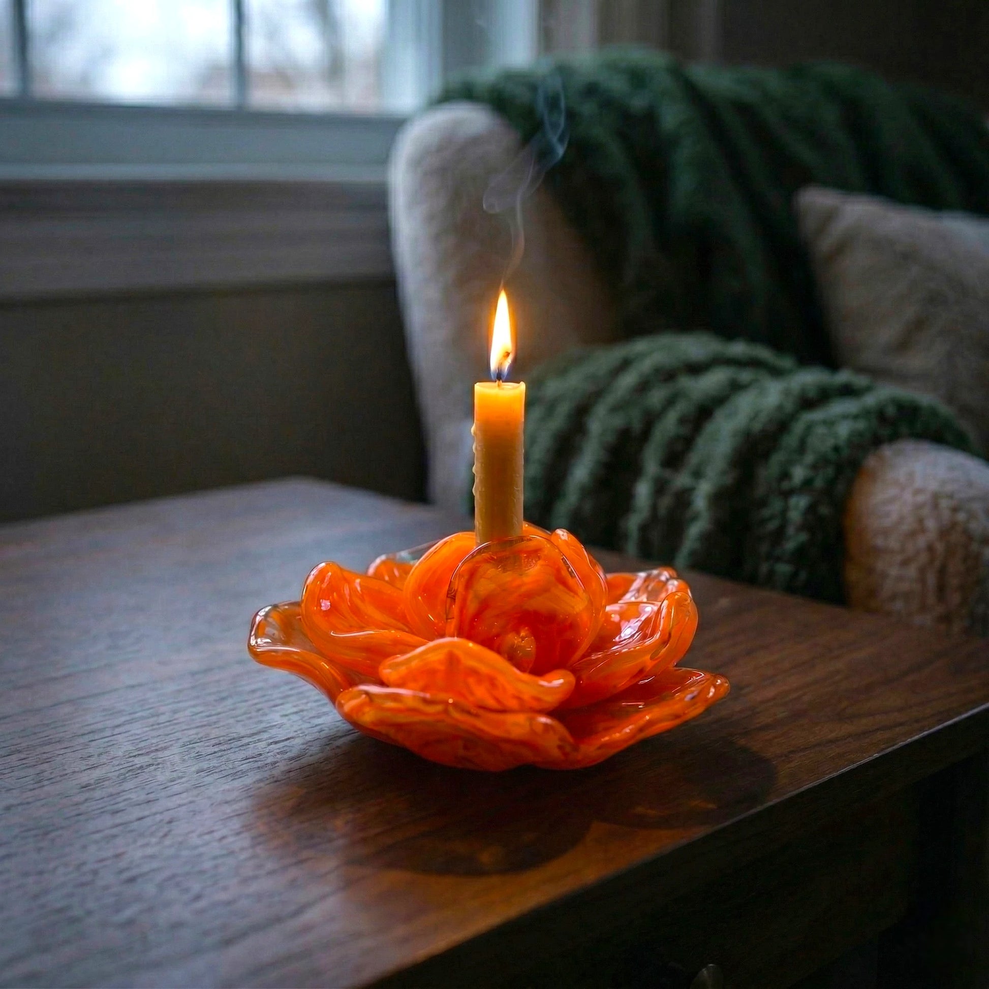 Orange flower holder lit, dark wood close-up