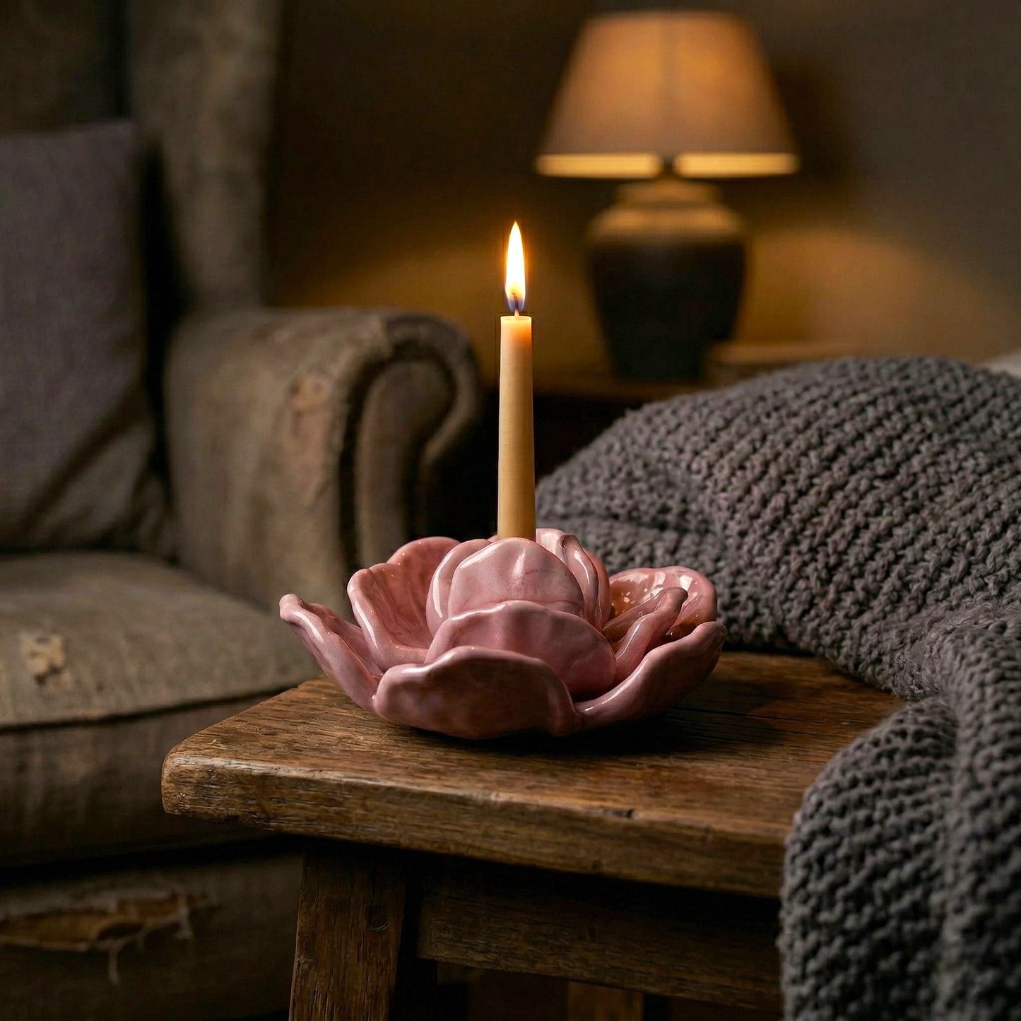 Pink flower holder lit on stool by sofa