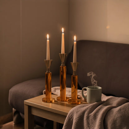 Set of three amber glass column candle holders with metallic flared tops and modern sculptural design