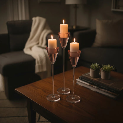 Three candles in glass holders on a wooden table in a dimly lit living room.