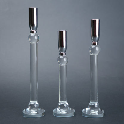 Three glass candle holders with silver bases on a gray background