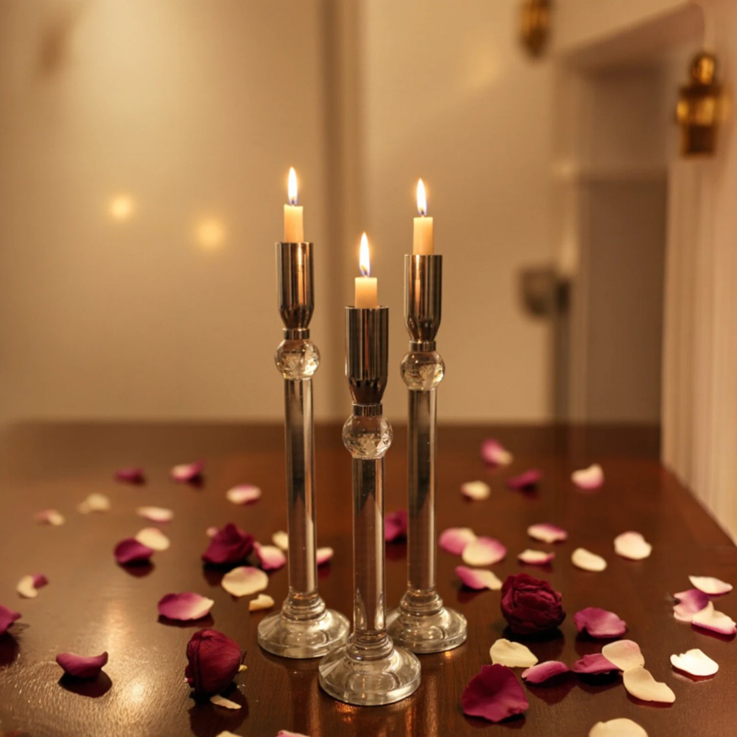 Set of three silver chrome candle holders with crystal stems and clear round bases arranged at varying heights