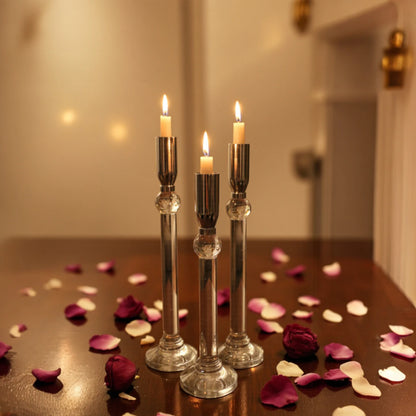 Set of three silver chrome candle holders with crystal stems and clear round bases arranged at varying heights