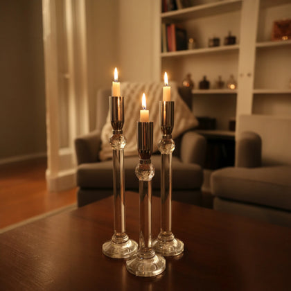Set of three silver chrome candle holders with crystal stems and clear round bases arranged at varying heights