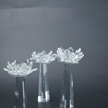 Three crystal lotus flower stands on a reflective surface with a dark background
