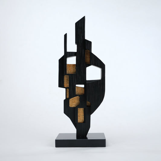 Abstract black decor object with geometric cut design and gold accents on base stand