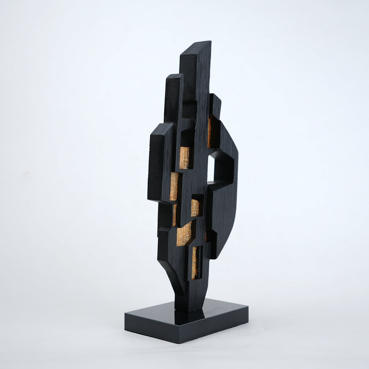 Abstract black decor object with geometric cut design and gold accents on base stand
