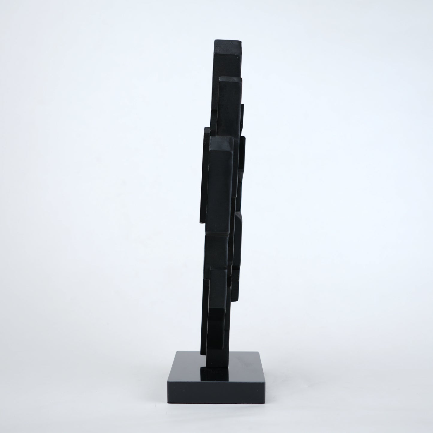 Abstract black decor object with geometric cut design and gold accents on base stand