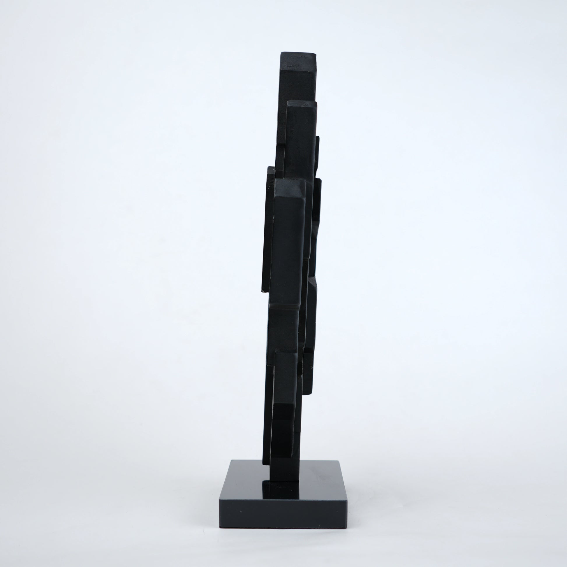 Abstract black decor object with geometric cut design and gold accents on base stand