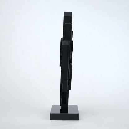 Abstract black decor object with geometric cut design and gold accents on base stand