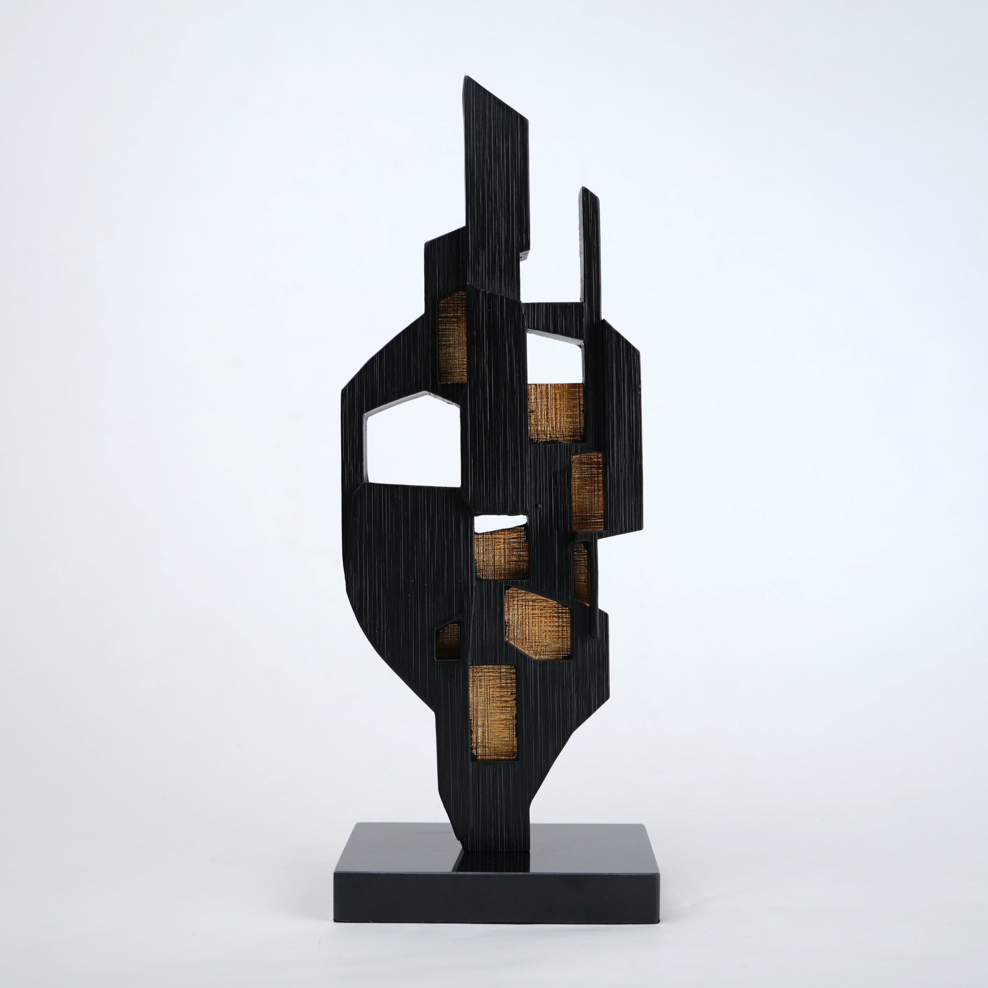 Abstract black decor object with geometric cut design and gold accents on base stand