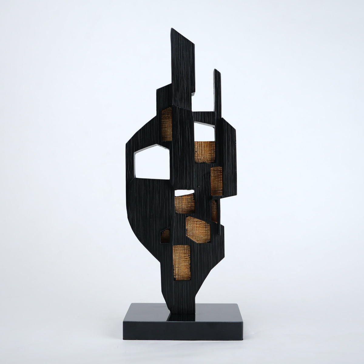 Abstract black decor object with geometric cut design and gold accents on base stand