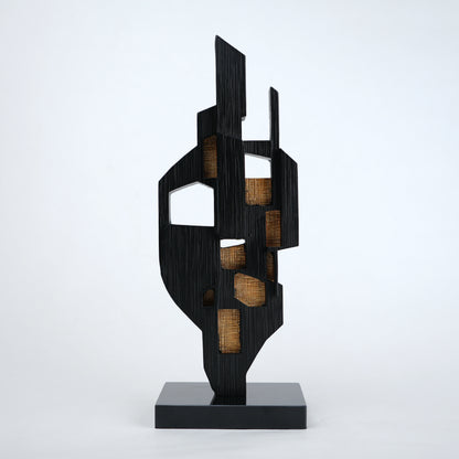 Abstract black decor object with geometric cut design and gold accents on base stand