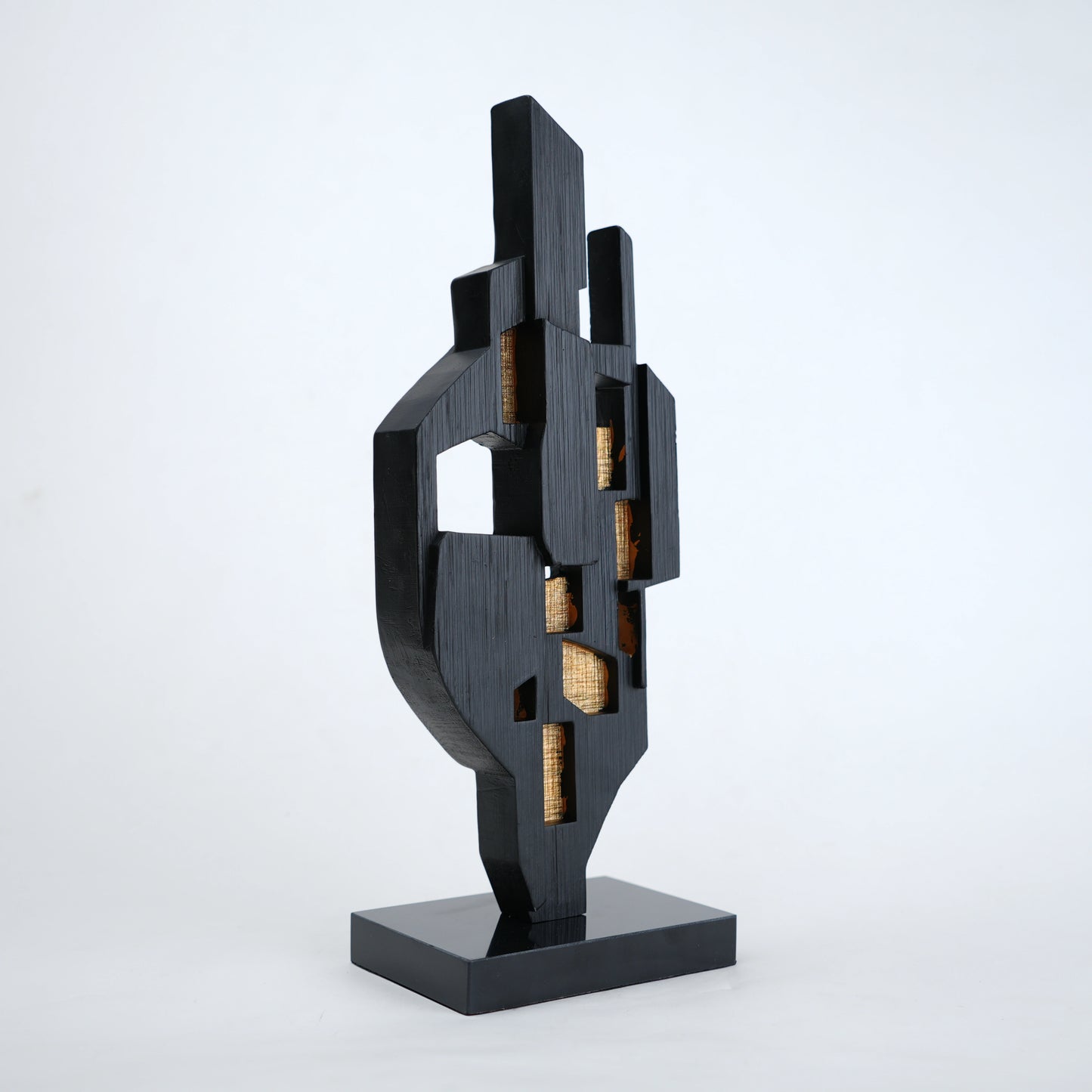 Abstract black decor object with geometric cut design and gold accents on base stand