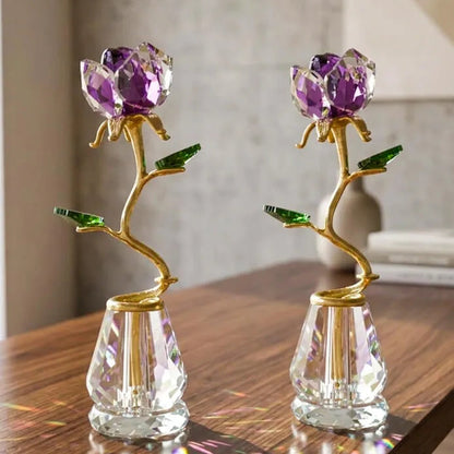 Two crystal flower vase decorations with purple faceted flower heads, gold stems, and green leaves, displayed on a wooden table.