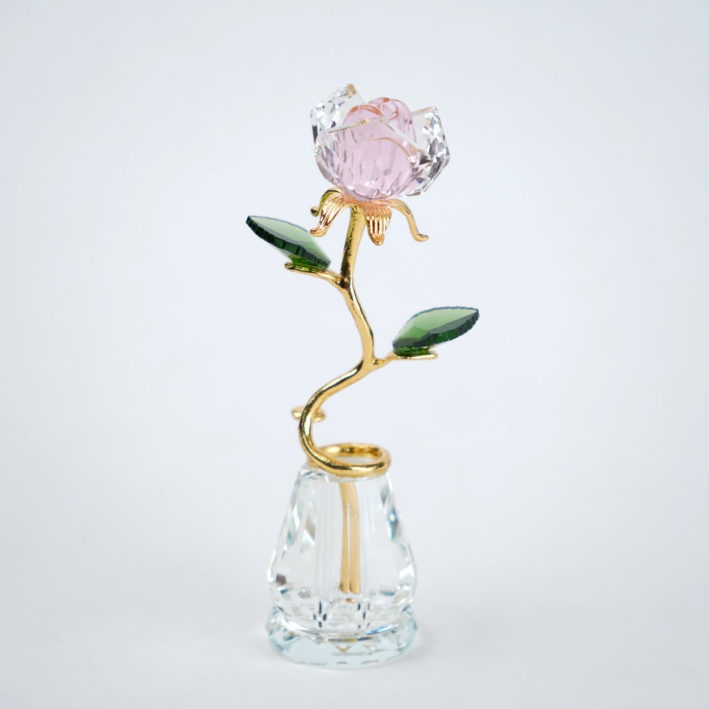 Decorative crystal flower with gold stem and pink petal on a clear base against a white background
