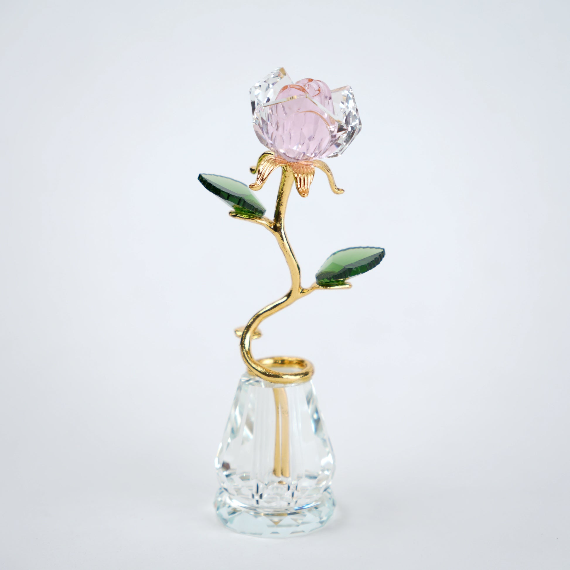 Decorative crystal flower with gold stem and pink petal on a clear base against a white background