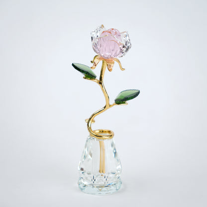 Decorative crystal flower with gold stem and pink petal on a clear base against a white background