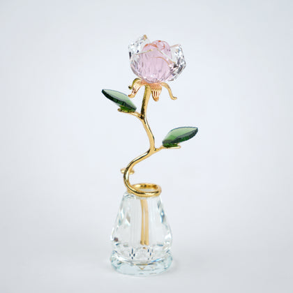 Decorative crystal flower with gold stem and pink petal on a clear base against a white background
