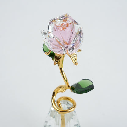 Crystal rose with gold stem and green leaves on a light gray background