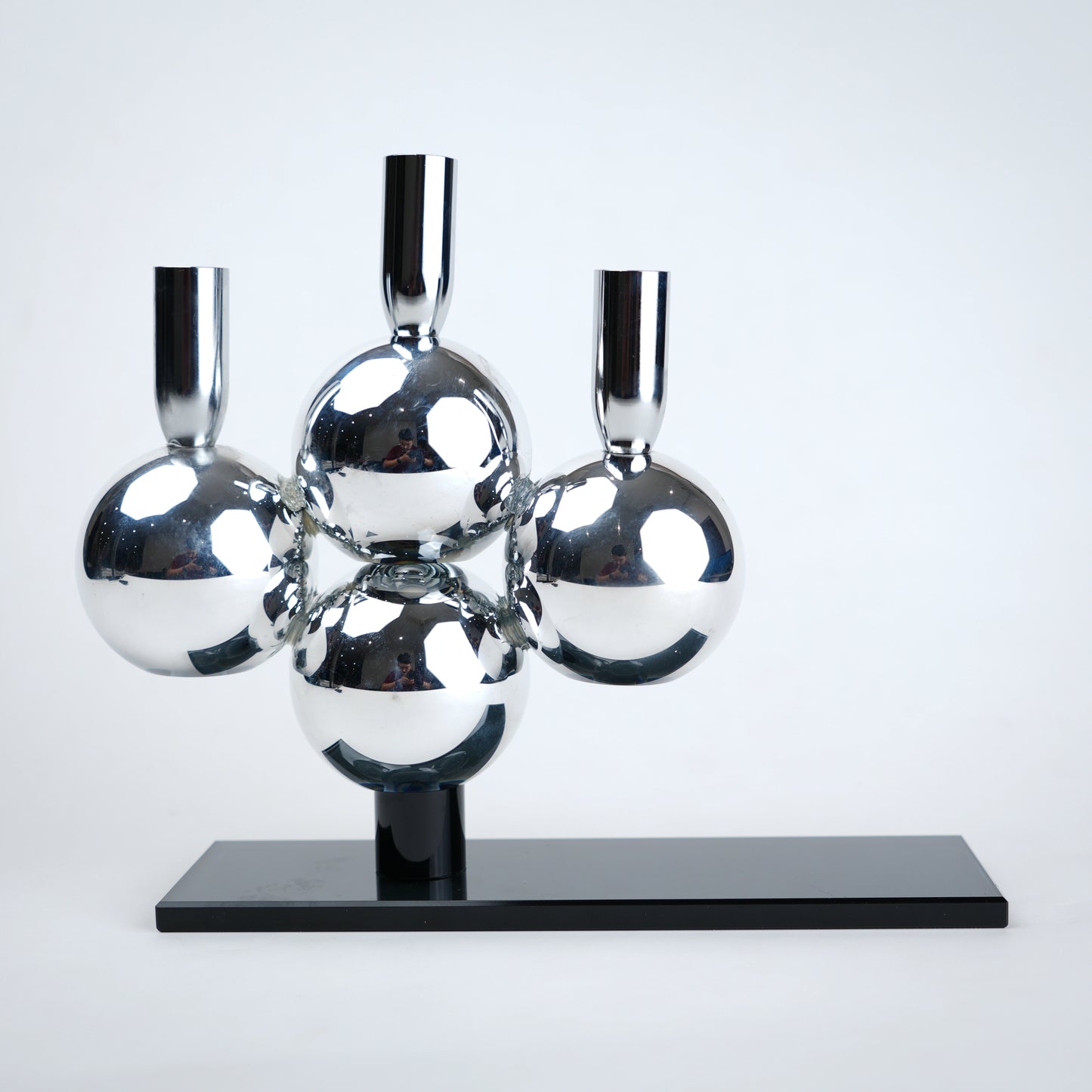 Metallic sphere sculpture on a black base against a white background