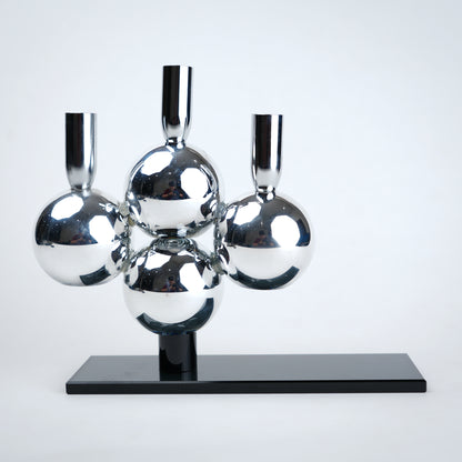 Metallic sphere sculpture on a black base against a white background