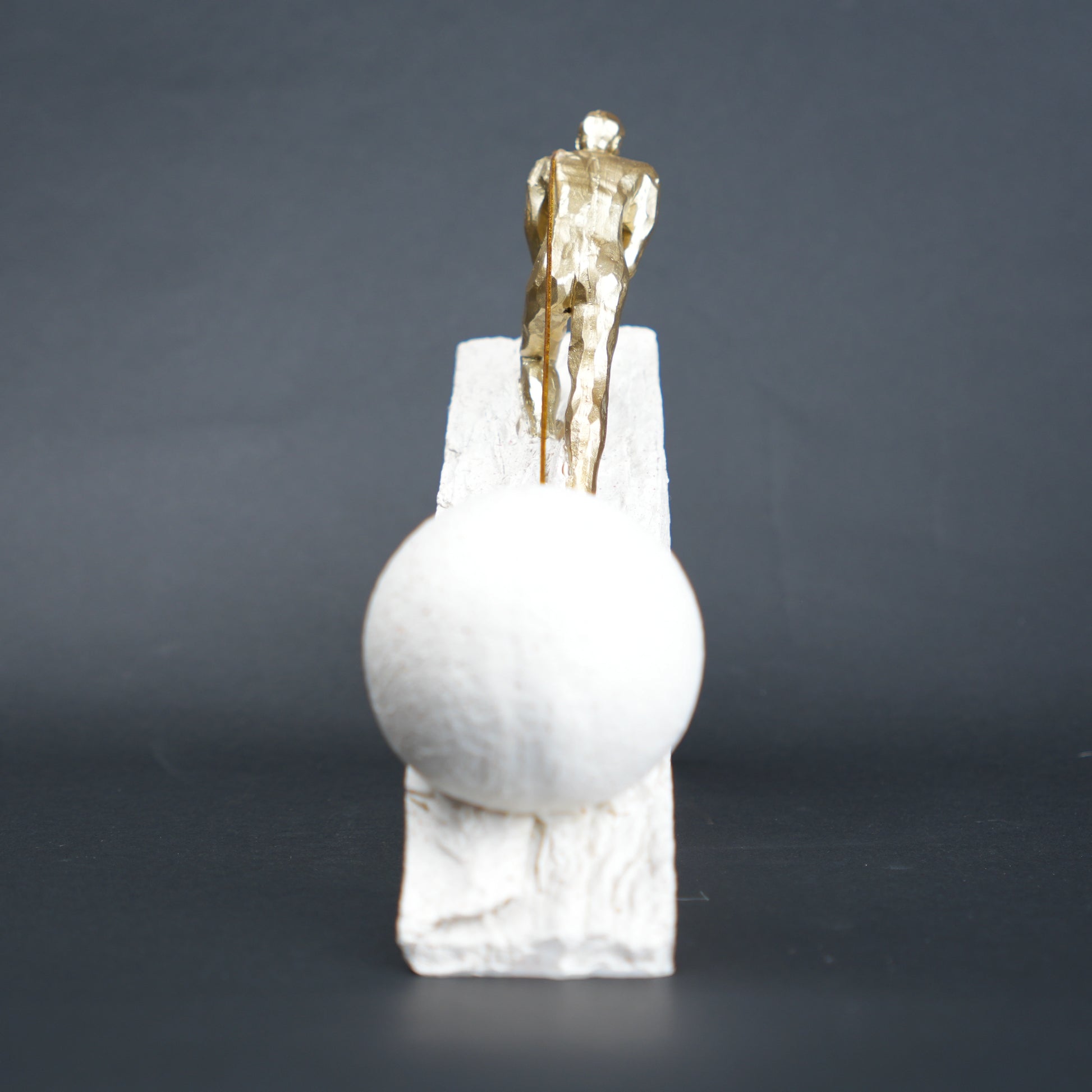 Gold climber figurine planting flag on textured stone incline base in black and white variants