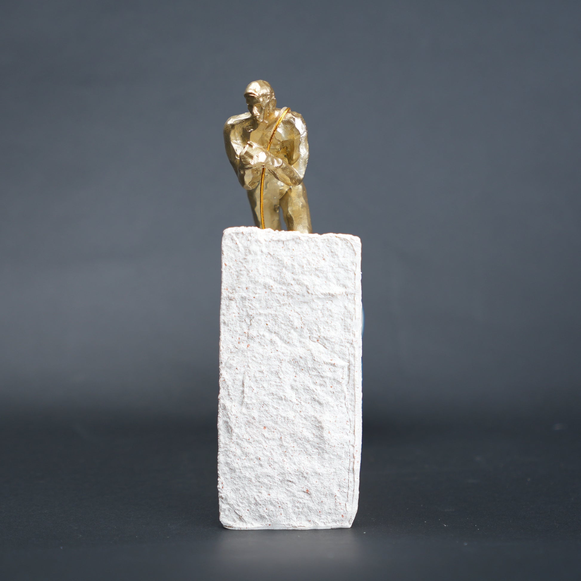 Gold climber figurine planting flag on textured stone incline base in black and white variants