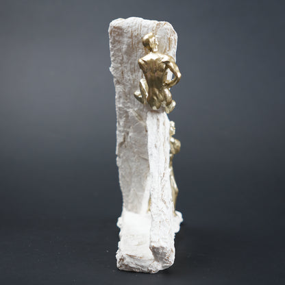 Gold figurine on a white rock-like structure against a dark background