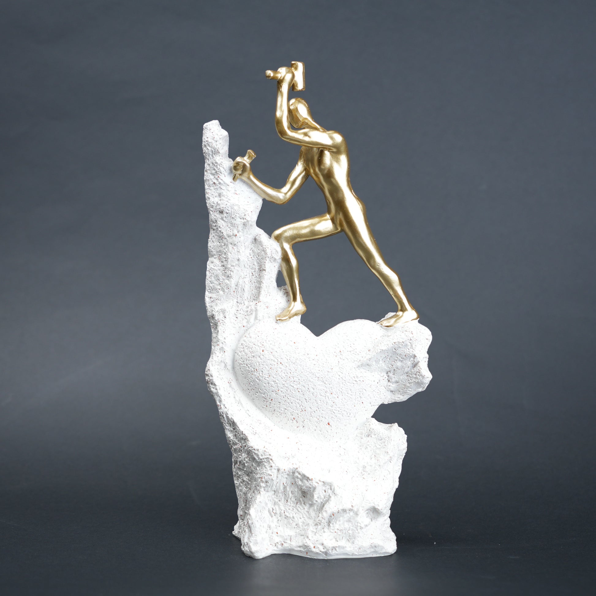Teamwork climber figurine with gold figures pushing metallic sphere on textured rock base in black and white variants
