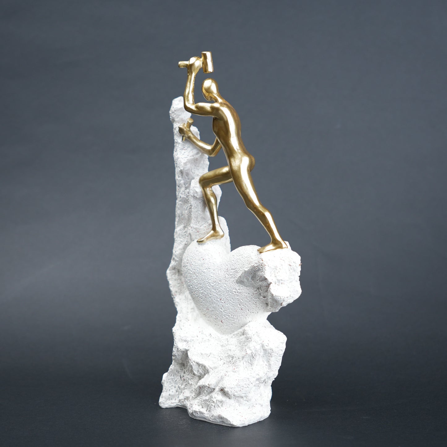 Teamwork climber figurine with gold figures pushing metallic sphere on textured rock base in black and white variants