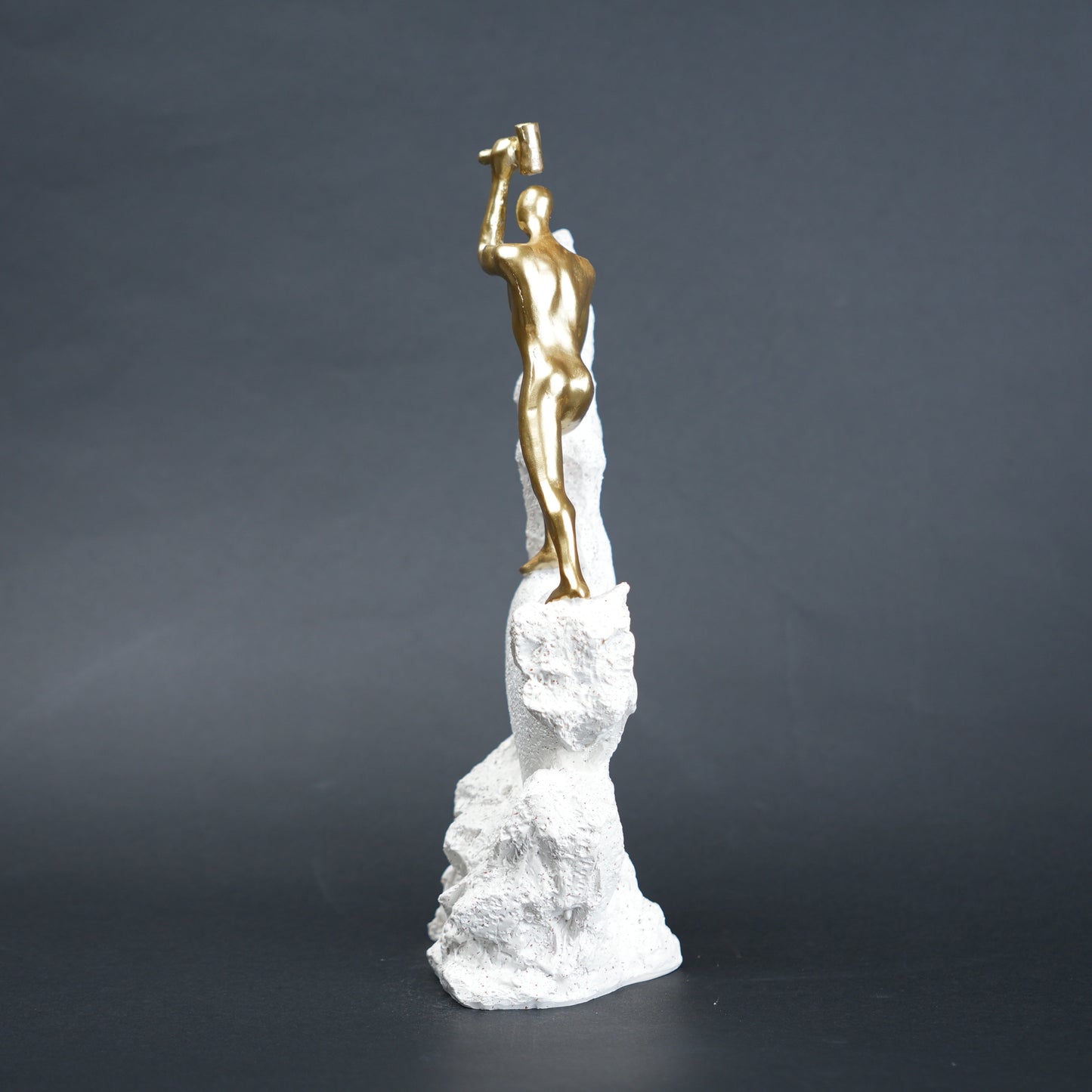 Teamwork climber figurine with gold figures pushing metallic sphere on textured rock base in black and white variants